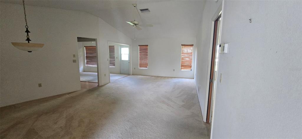An interior view of a carpeted living area with a vaulted ceiling and ceiling fan — 665 FOXWOOD BOULEVARD, ENGLEWOOD, FL