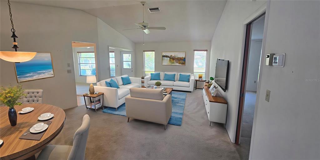A living room and dining area feature white sofas, a blue rug, and vaulted ceilings — 665 FOXWOOD BOULEVARD, ENGLEWOOD, FL