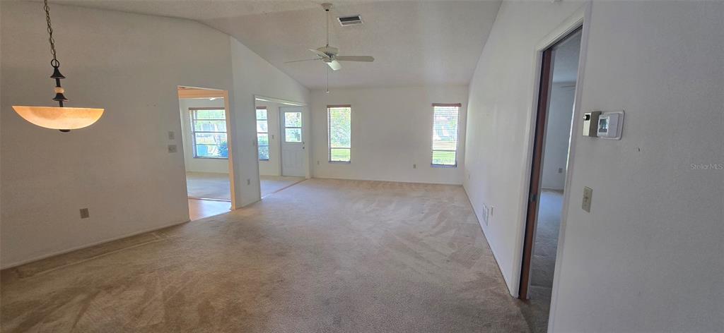 A living room with beige carpeting, a vaulted ceiling, a ceiling fan, and multiple windows — 665 FOXWOOD BOULEVARD, ENGLEWOOD, FL