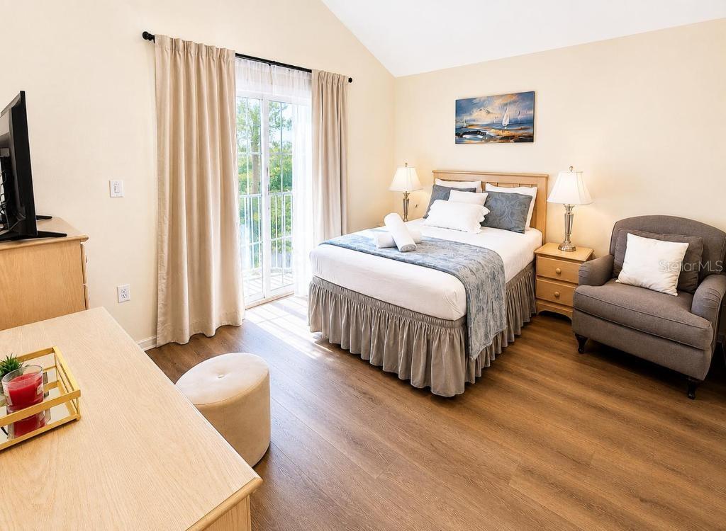 A bedroom features a bed, armchair, dresser, and sliding glass doors leading to a balcony — 176 HARPERSFIELD STREET, DAVENPORT, FL