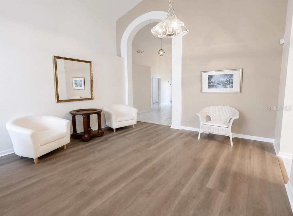 A living area features light wood-look flooring, white armchairs, and an arched entryway — 176 HARPERSFIELD STREET, DAVENPORT, FL