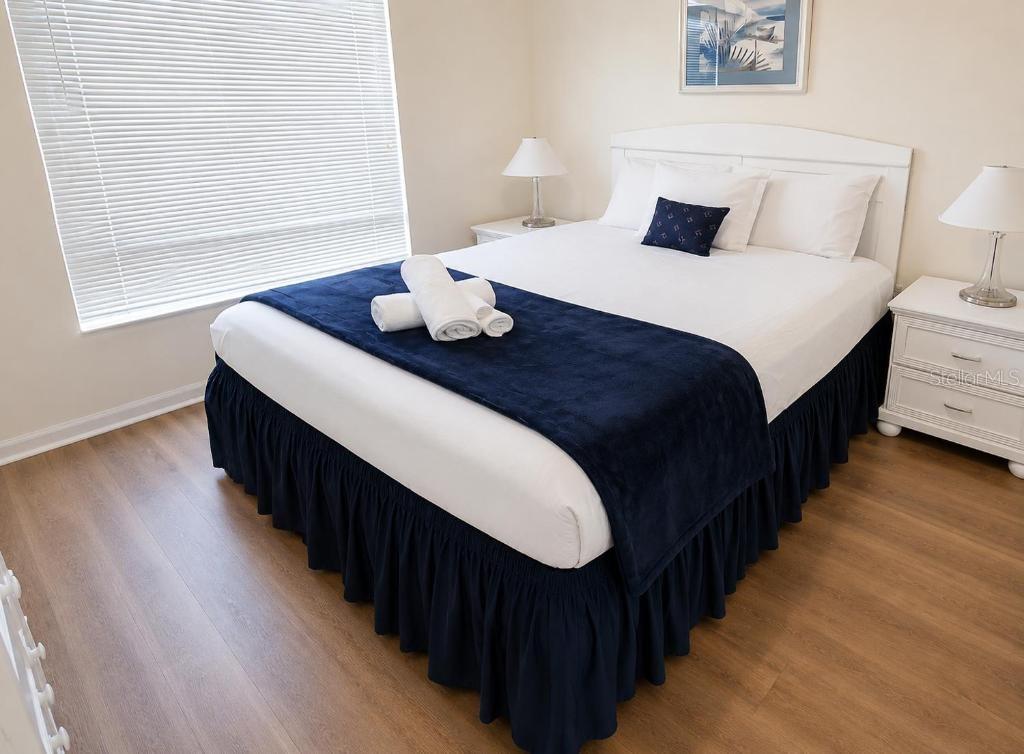 A bedroom features a bed with a navy blue runner and skirt on wood flooring — 176 HARPERSFIELD STREET, DAVENPORT, FL