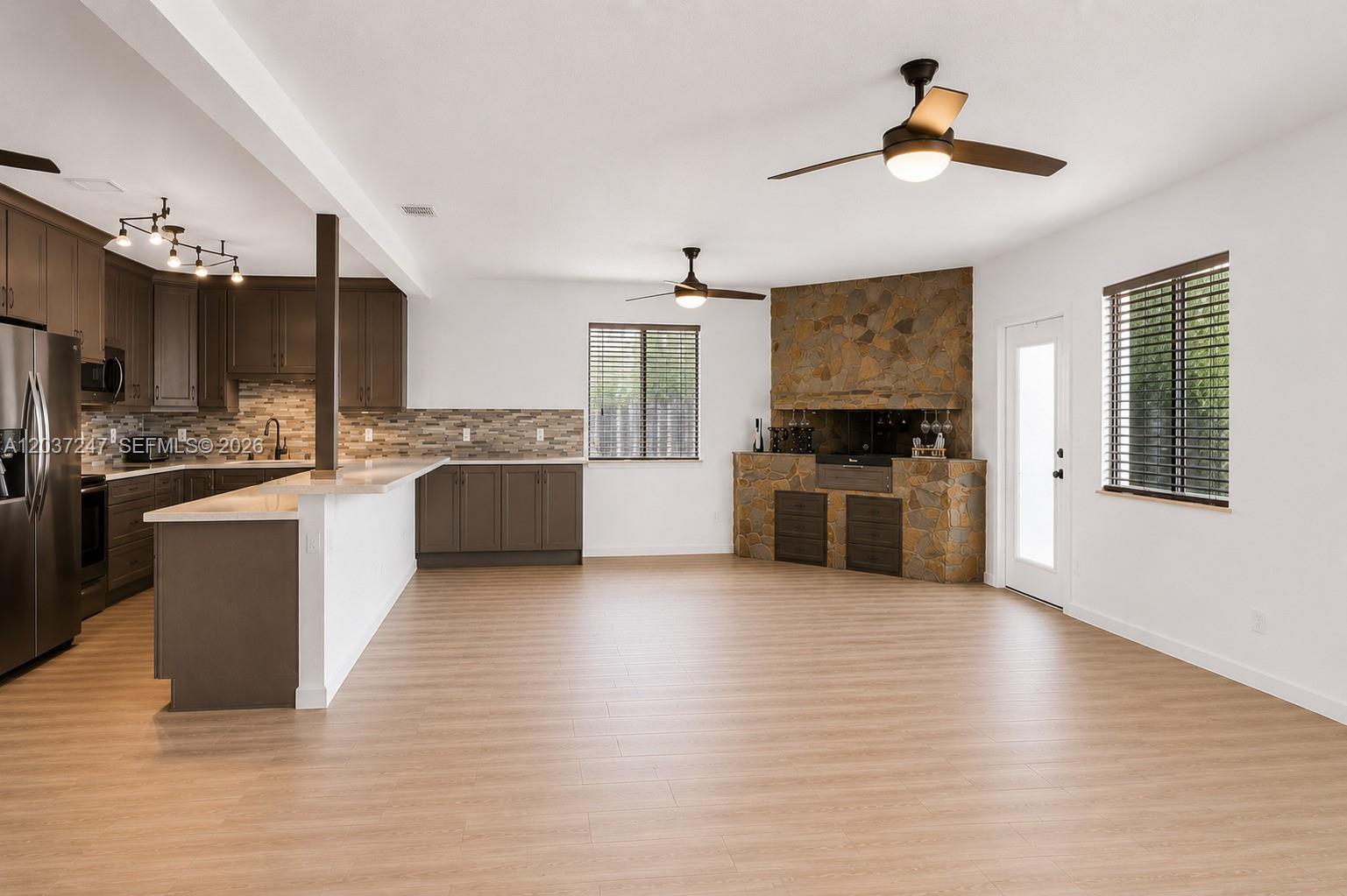 A kitchen and living area feature dark cabinets, light wood floors, and a stone fireplace — 316 NW 29th St, Wilton Manors FL 33311, WILTON MANORS, FL