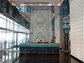 A modern lobby features a reception desk, a large marble accent wall, and mirrored ceilings — 335 S Biscayne Blvd # 2006, Miami FL 33131, MIAMI, FL