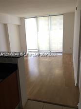 An empty room with light wood flooring and large floor-to-ceiling windows — 335 S Biscayne Blvd # 2006, Miami FL 33131, MIAMI, FL