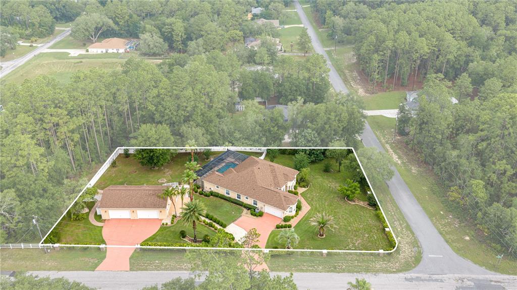 An aerial view shows a single-story house with a pool enclosure and two driveways — 5296 N PRINCEWOOD DRIVE, BEVERLY HILLS, FL
