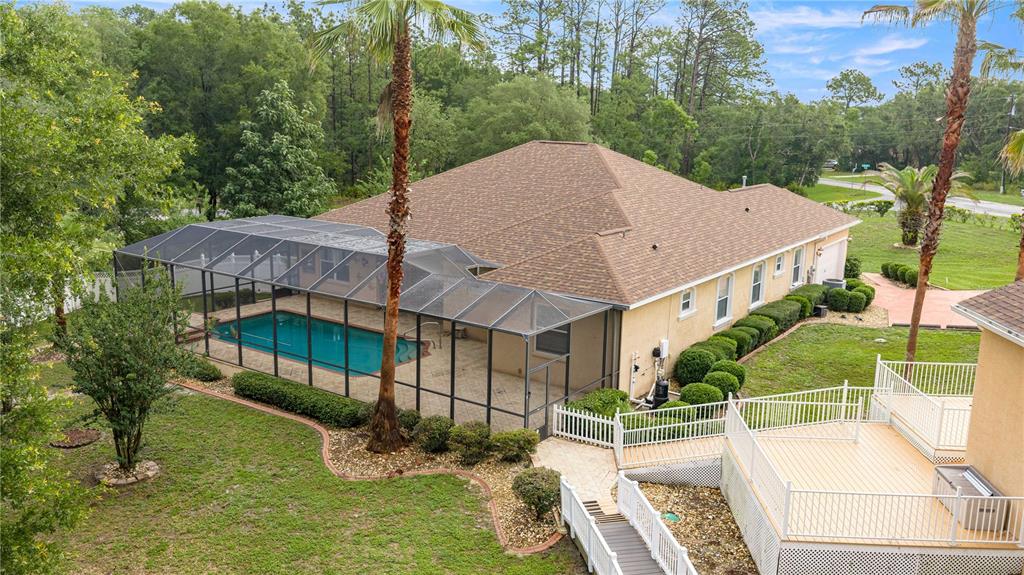 An aerial view of a house with a screened-in pool, a wooden deck, and landscaping — 5296 N PRINCEWOOD DRIVE, BEVERLY HILLS, FL