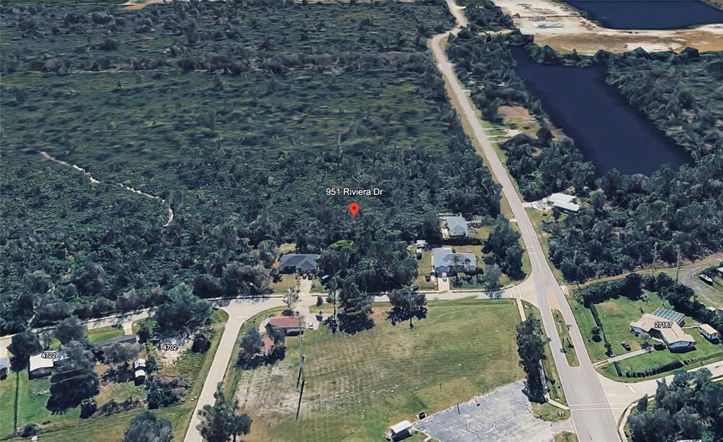 An aerial view shows a wooded residential lot with a red location pin — 951 RIVIERA DRIVE, PUNTA GORDA, FL