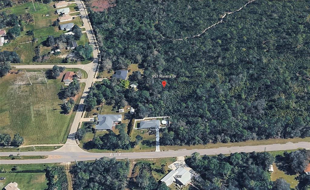 An aerial view shows a residential lot with dense trees and nearby houses — 951 RIVIERA DRIVE, PUNTA GORDA, FL