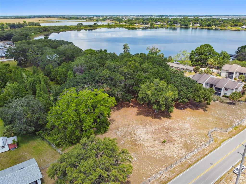 An aerial view shows a vacant, grassy lot bordered by a road, trees, and a lake — 1080 S BUENA VISTA DRIVE, LAKE ALFRED, FL
