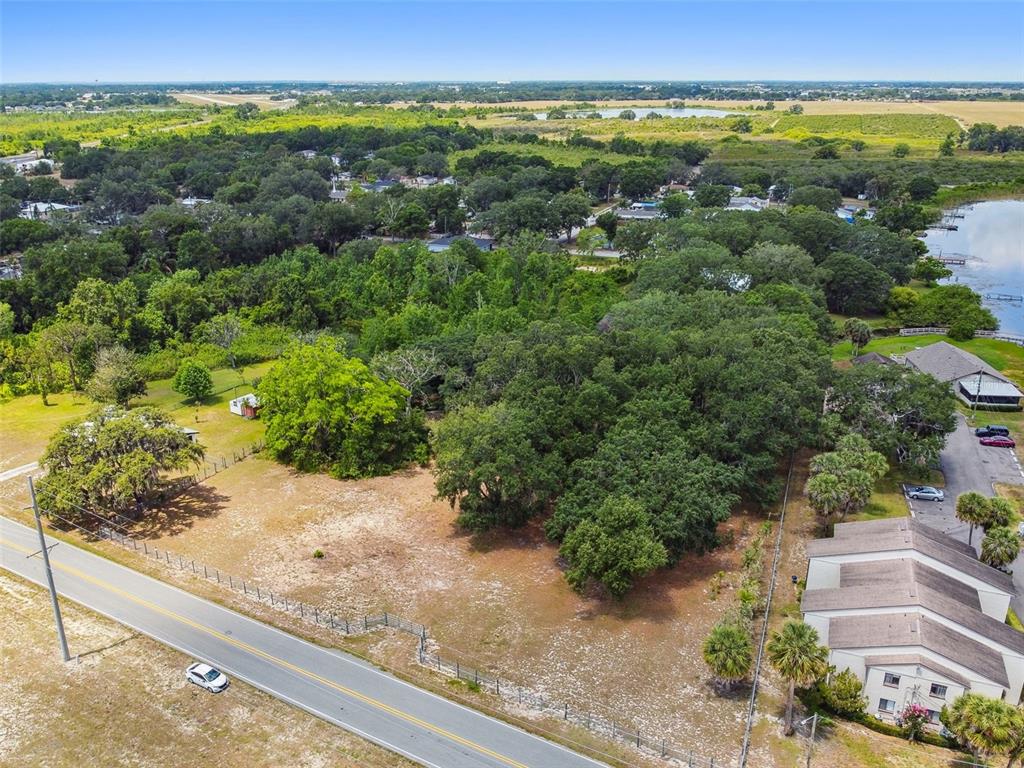 An aerial view shows a vacant, partially wooded lot adjacent to a road and buildings — 1080 S BUENA VISTA DRIVE, LAKE ALFRED, FL