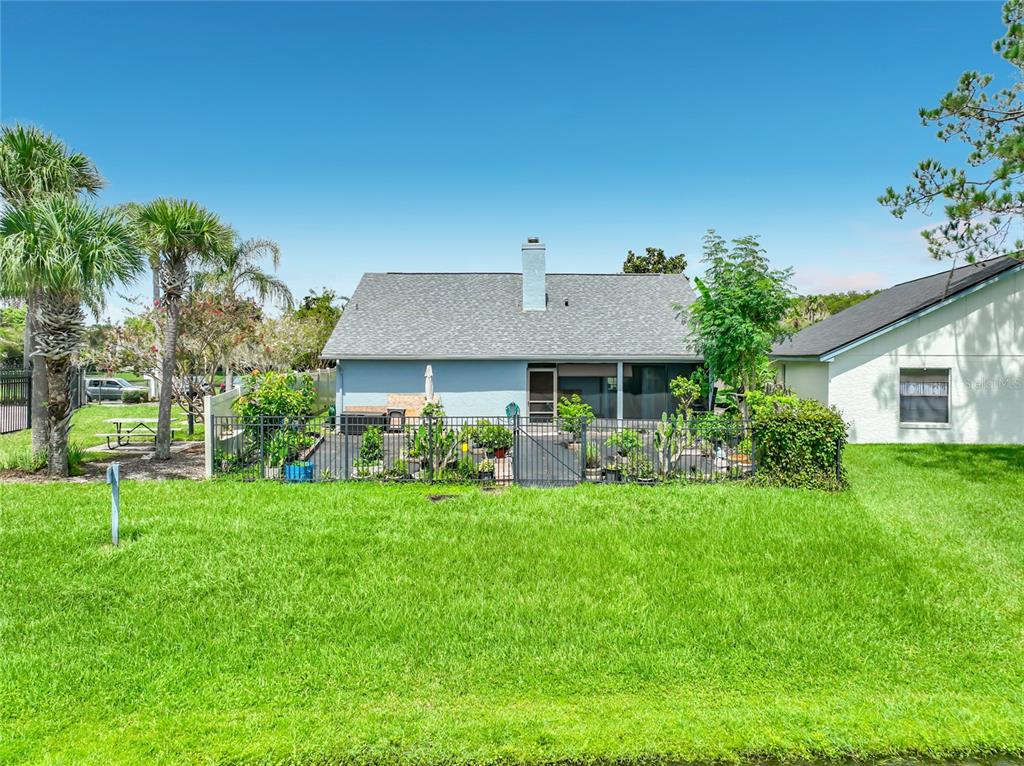 The exterior of a light blue house features a fenced patio area and palm trees — 2405 SETTLERS TRAIL, ORLANDO, FL