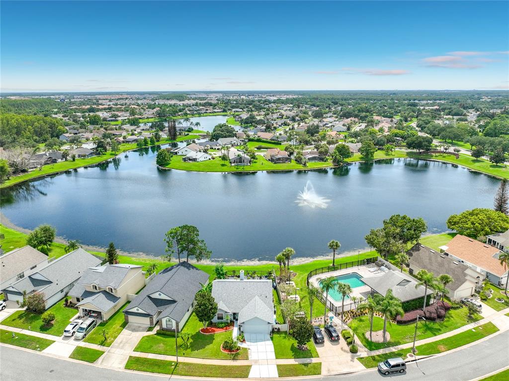 An aerial view of a suburban neighborhood featuring houses surrounding a large lake with a fountain — 2405 SETTLERS TRAIL, ORLANDO, FL