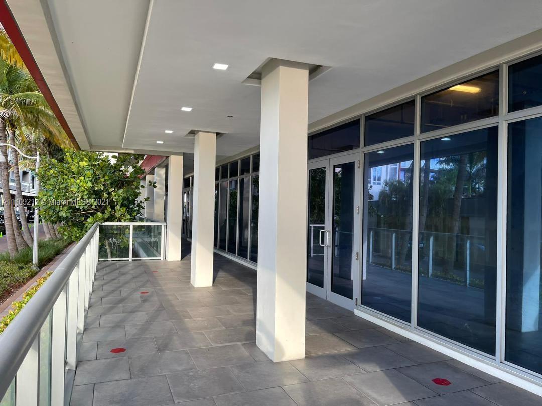 A covered outdoor walkway features gray tile flooring, white support columns, and glass storefront doors — 777 N Ocean Dr # N107, Hollywood FL 33019, HOLLYWOOD, FL