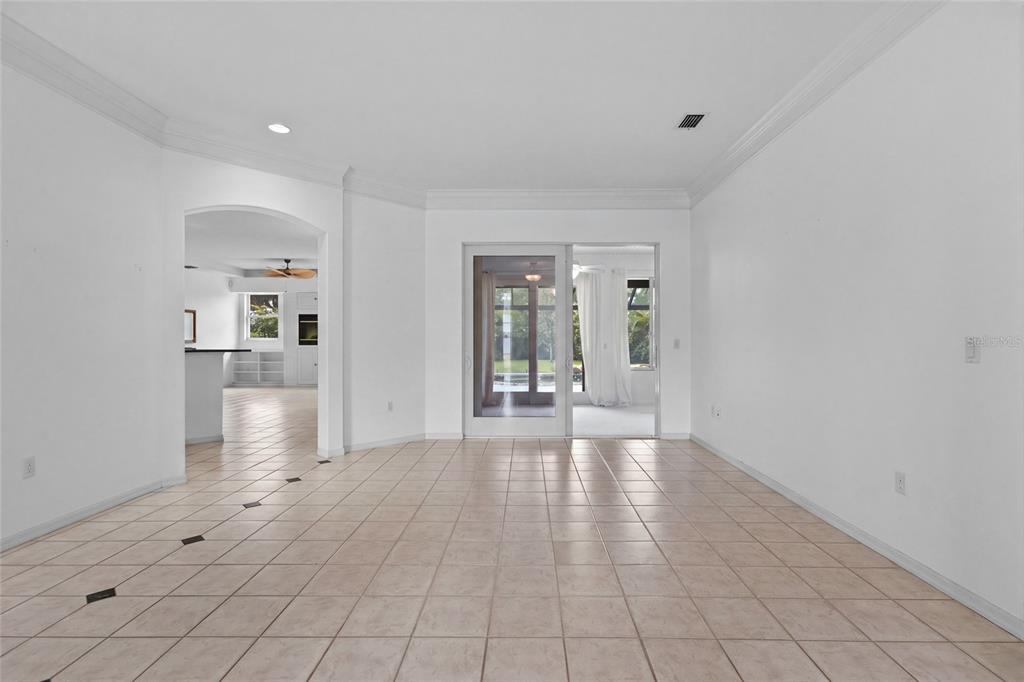A bright, tiled living room features an arched entryway and sliding glass doors to a patio — 3732 COUNTRYSIDE ROAD, SARASOTA, FL