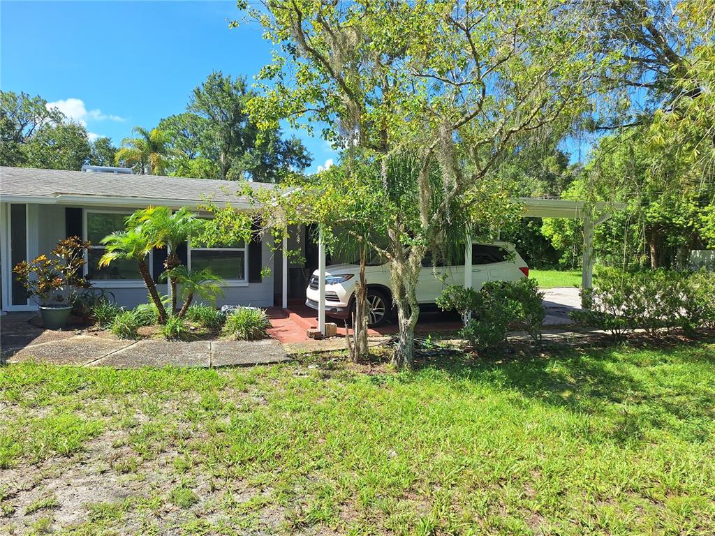 A single-story house with a carport, a white SUV, and landscaping in the front yard — 7606 VAN DYKE ROAD, ODESSA, FL