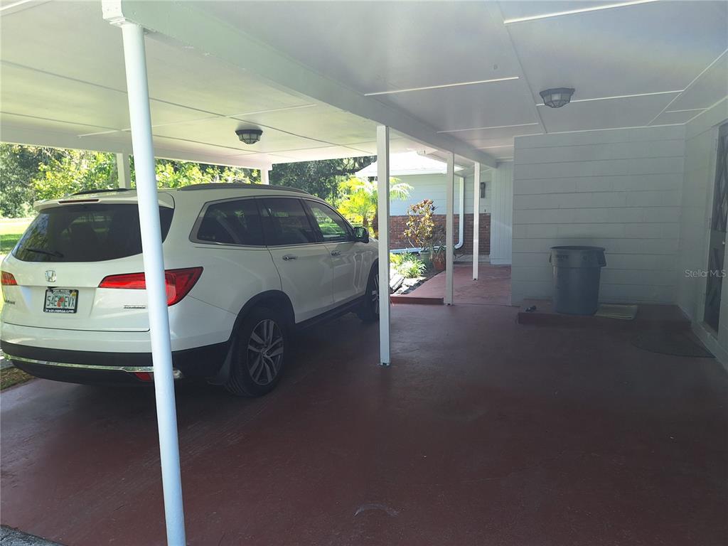 A white SUV is parked under a covered carport with a concrete floor — 7606 VAN DYKE ROAD, ODESSA, FL
