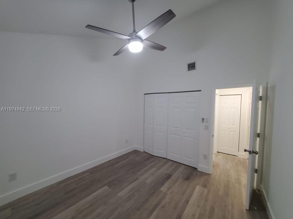 An empty bedroom features white walls, wood-look flooring, a ceiling fan, and a closet — NORTH LAUDERDALE, FL