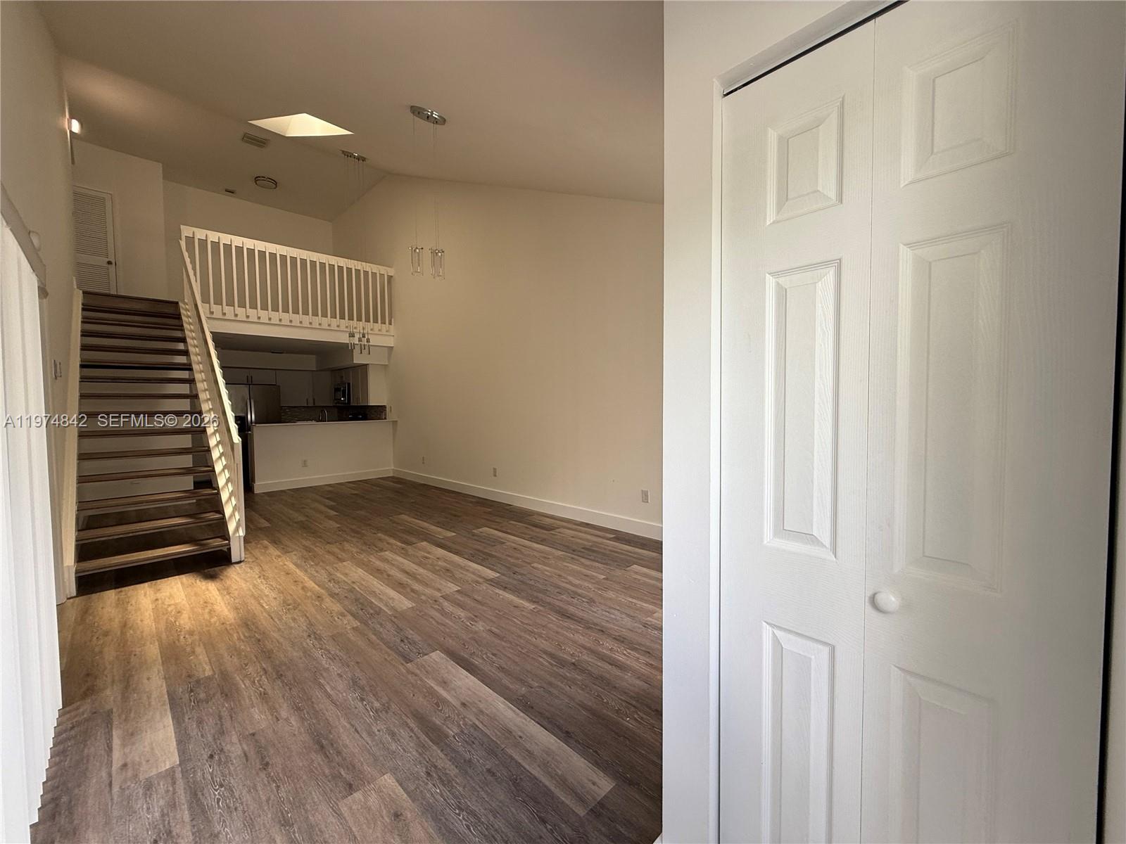 A living room features wood-look flooring, a staircase, a loft area, and a kitchen view — NORTH LAUDERDALE, FL