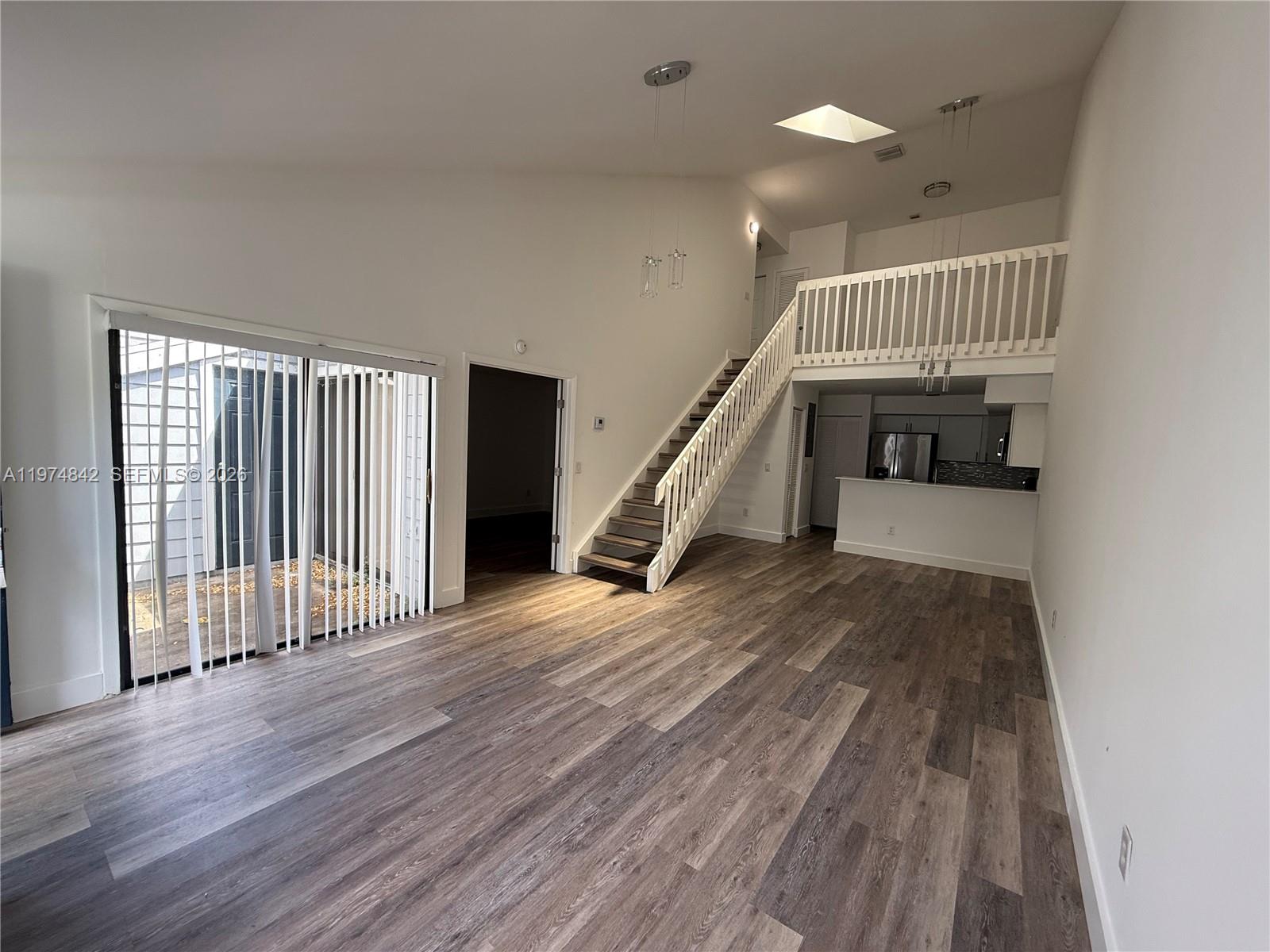 A living room features wood-look flooring, a staircase, a loft, and a sliding glass door — NORTH LAUDERDALE, FL
