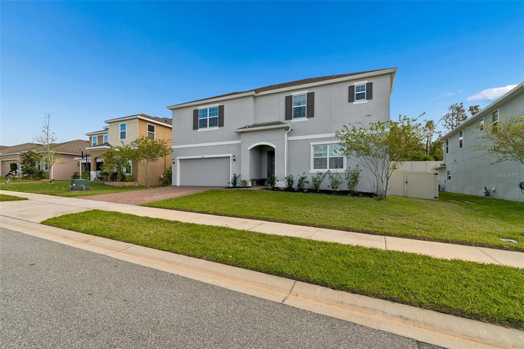 A two-story gray house with a two-car garage and a front lawn — 1084 CAVENDER CREEK ROAD, MINNEOLA, FL