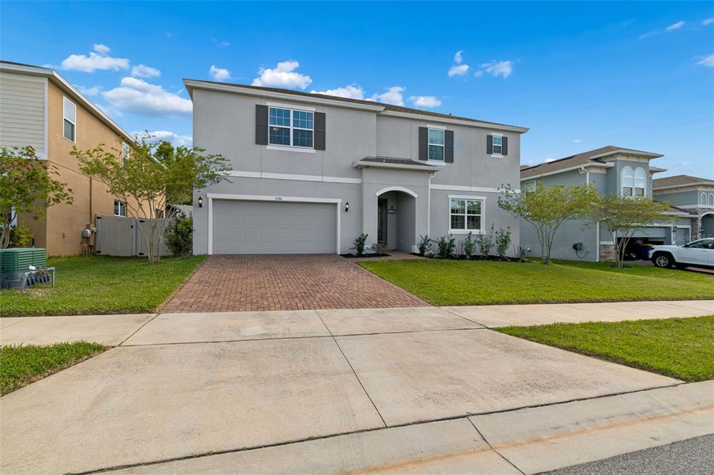 A two-story suburban house with a gray stucco exterior, a two-car garage, and a driveway — 1084 CAVENDER CREEK ROAD, MINNEOLA, FL