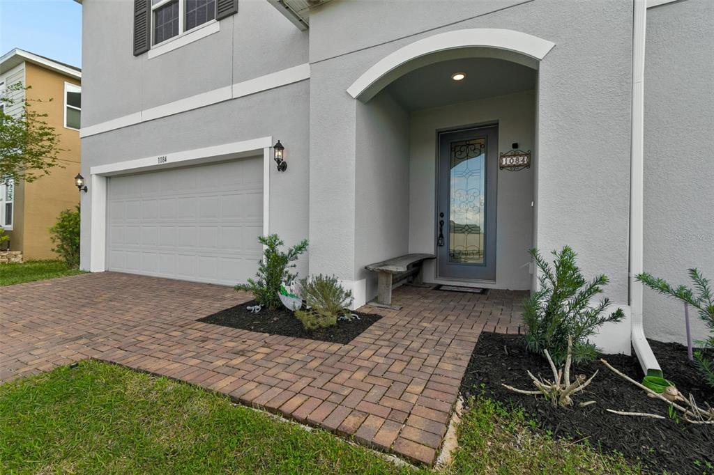 A gray two-story house features a brick paver driveway, a covered entryway, and a garage — 1084 CAVENDER CREEK ROAD, MINNEOLA, FL