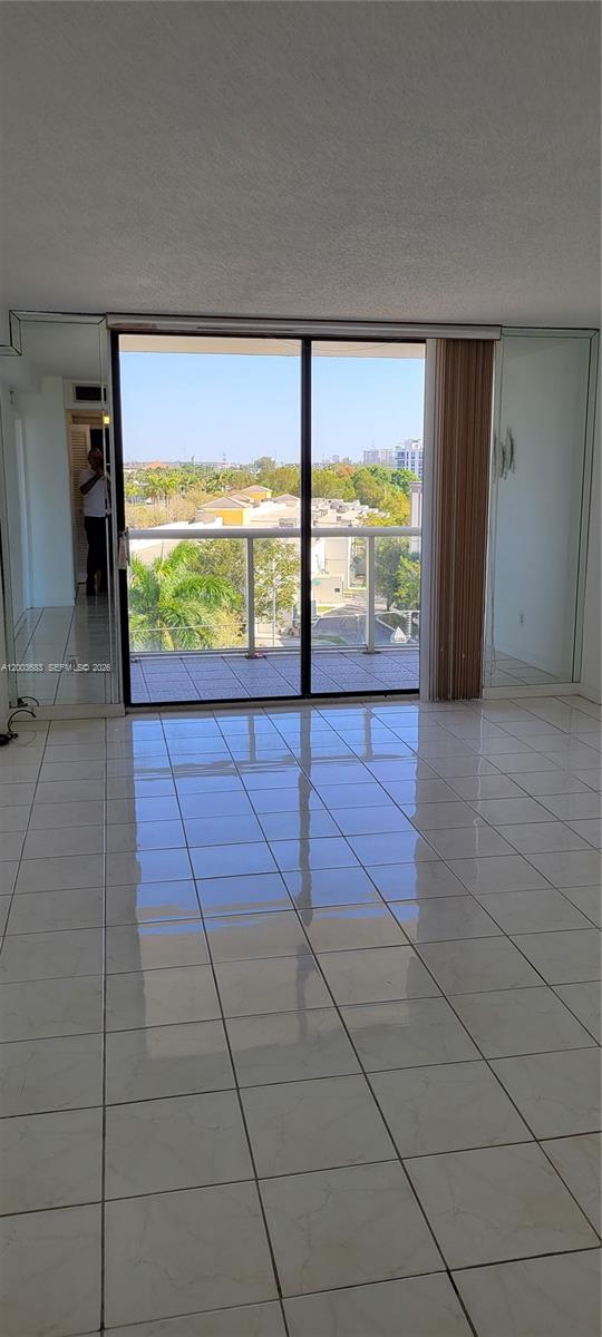 A bright room with white tiled floors, mirrored walls, and a sliding glass door to a balcony — 13499 Biscayne Blvd # 511, North Miami FL 33181, NORTH MIAMI, FL