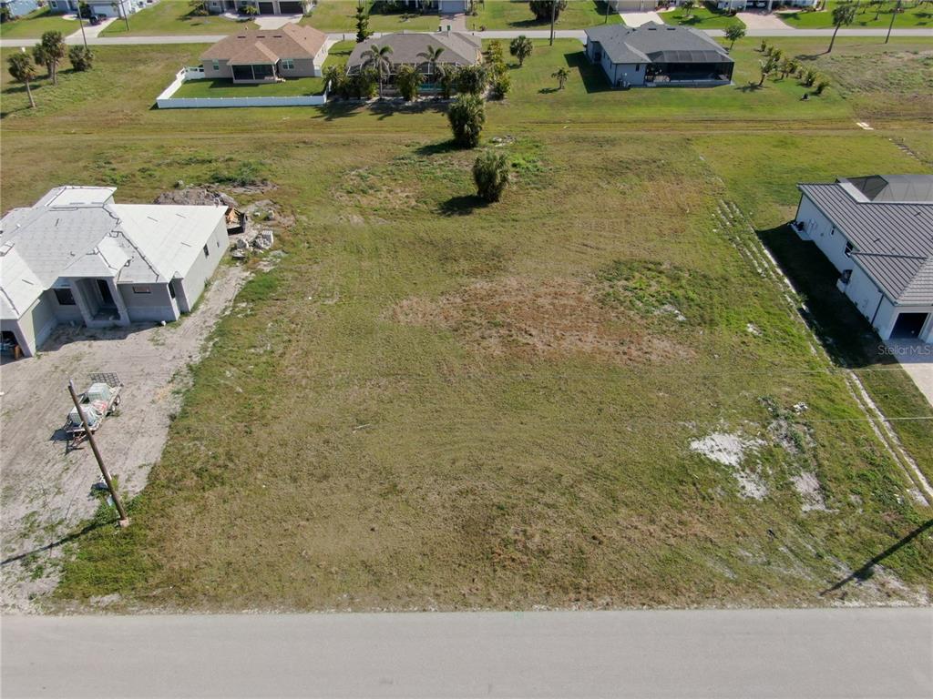 An aerial view shows a vacant residential lot situated between two houses on a paved street — 189 ROTONDA BOULEVARD S, ROTONDA WEST, FL