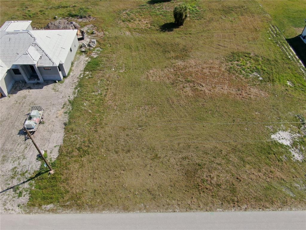 An aerial view shows a vacant, grassy residential lot next to a house under construction — 189 ROTONDA BOULEVARD S, ROTONDA WEST, FL