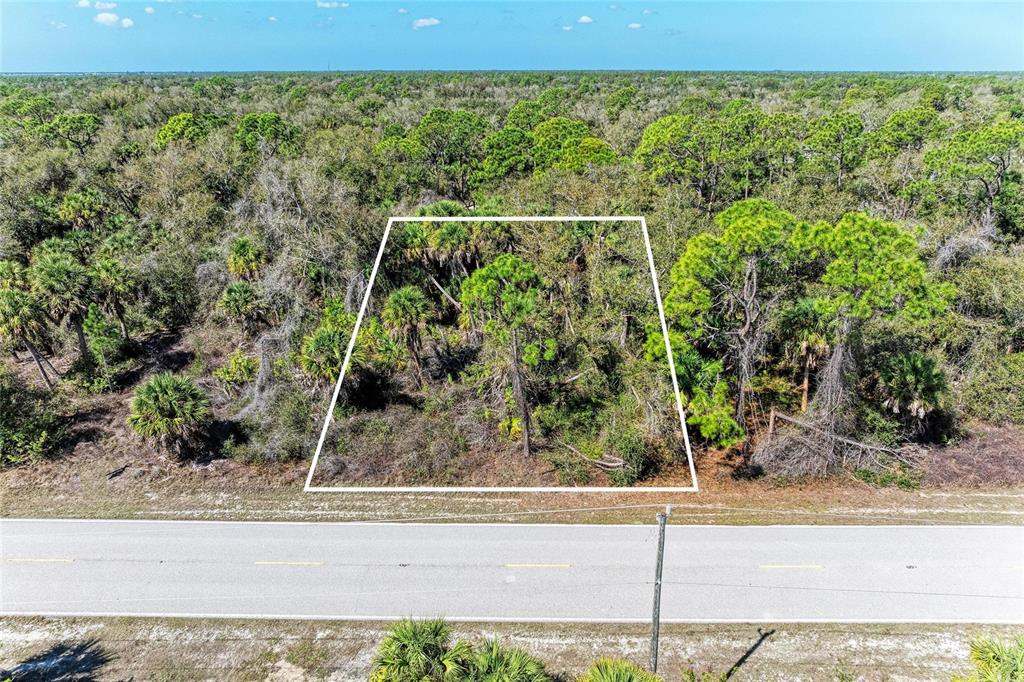 An aerial view shows a rectangular plot of undeveloped land bordering a paved road — 3115 COMO STREET, PORT CHARLOTTE, FL
