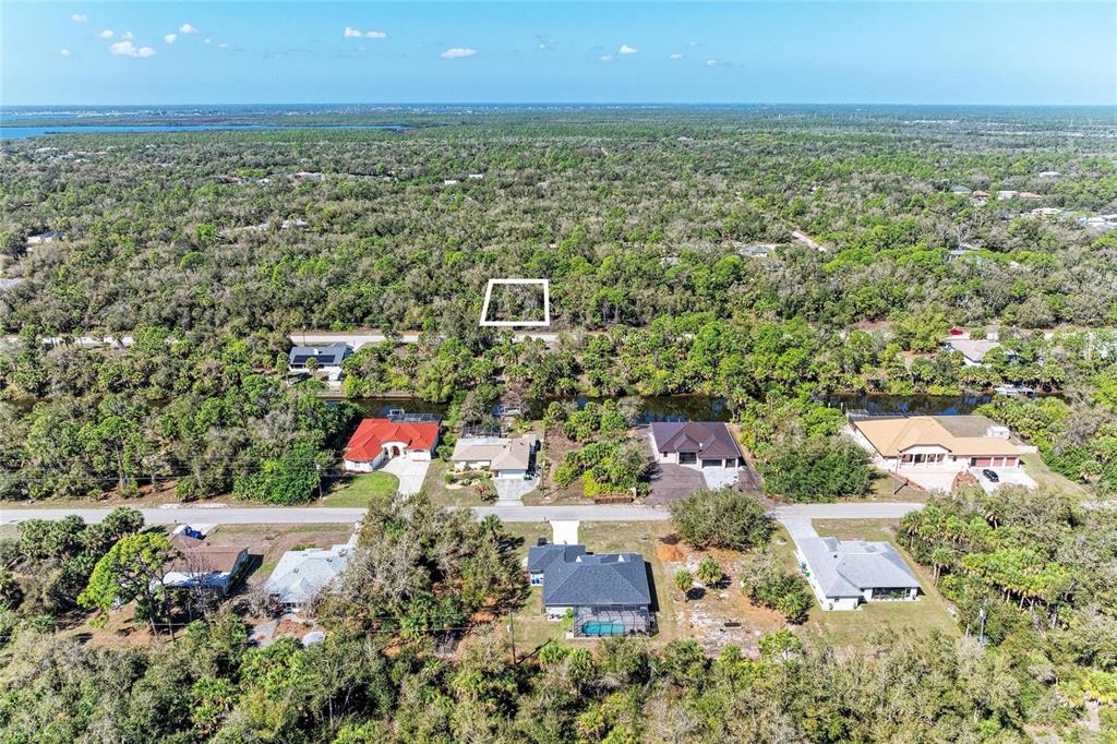 An aerial view shows several houses with pools situated along a canal amidst dense trees — 3115 COMO STREET, PORT CHARLOTTE, FL