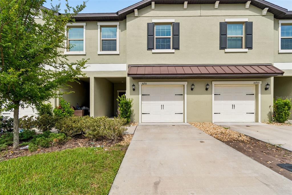 A two-story townhouse exterior with two white garage doors and a concrete driveway — 30751 VERIDIAN WAY, WESLEY CHAPEL, FL