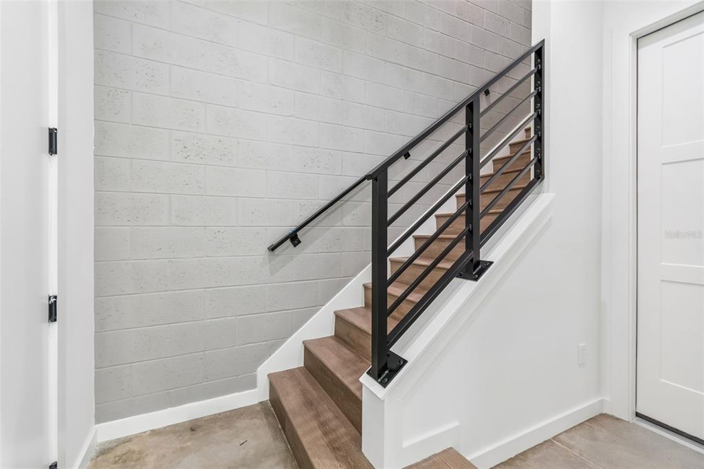 A staircase with wood treads and a black metal railing against a gray block wall — 1218 E KAY STREET UNIT 21, TAMPA, FL