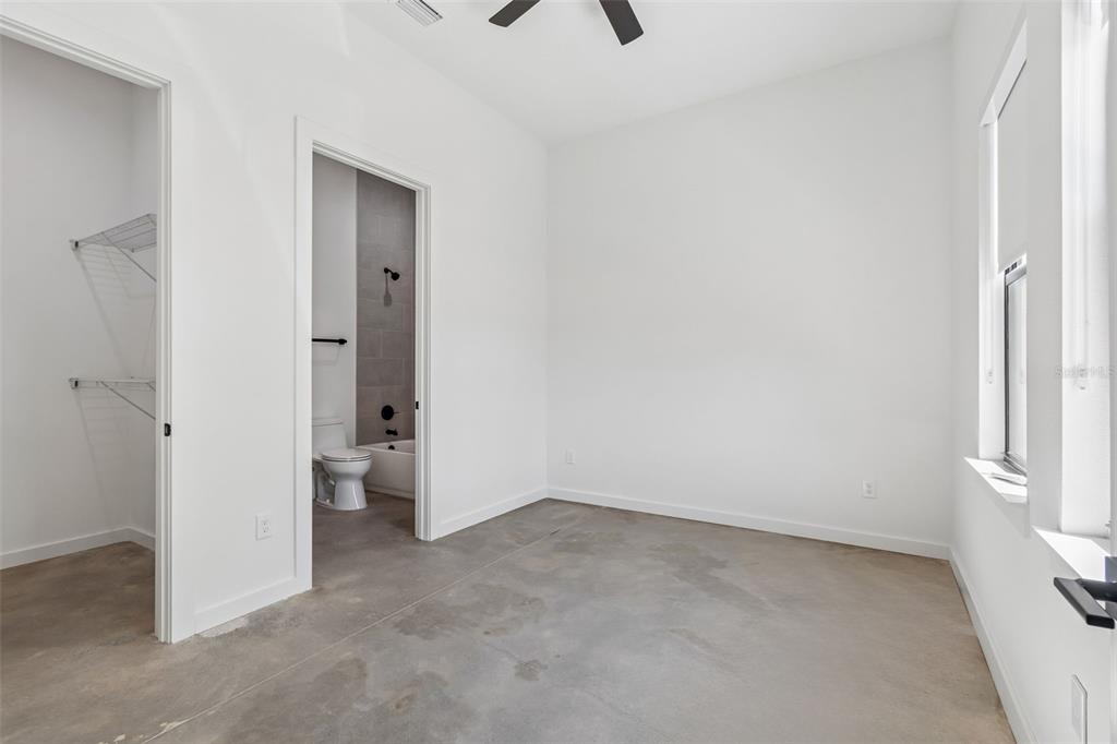 A bedroom with concrete floors, a walk-in closet, and an attached bathroom with a tub — 1218 E KAY STREET UNIT 21, TAMPA, FL