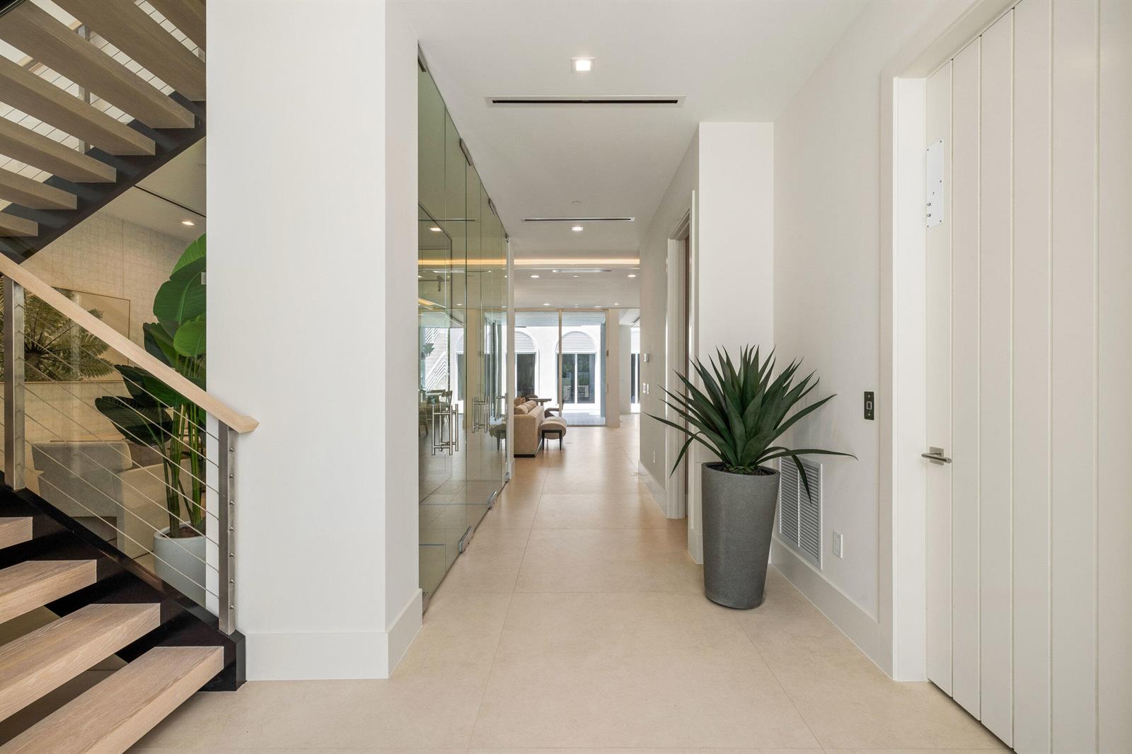 A bright hallway features light tile floors, a glass-walled room, and a modern staircase — 812 Palm Trail, Delray Beach FL 33483, DELRAY BEACH, FL