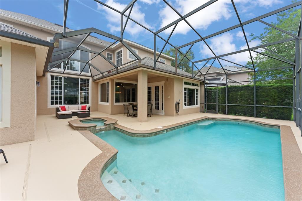 A screened-in patio features a swimming pool, a hot tub, and outdoor seating — 14411 HAMPSHIRE BAY CIRCLE, WINTER GARDEN, FL