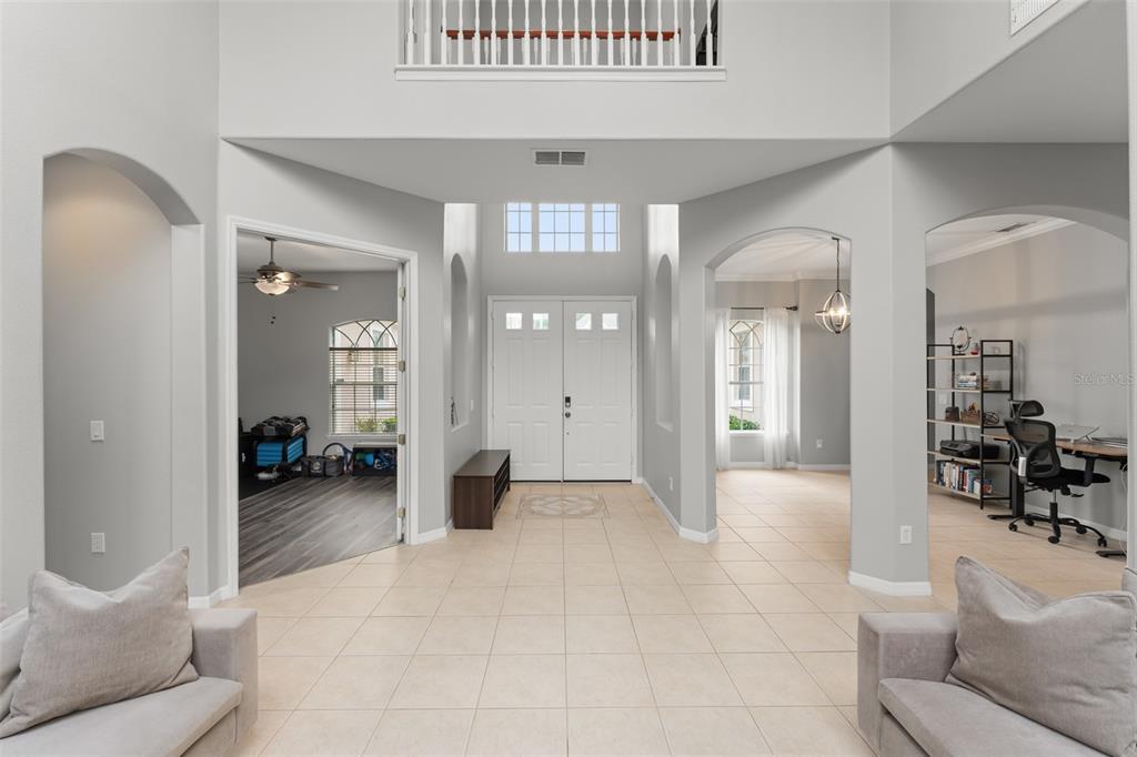 A bright, two-story foyer features light tile flooring, arched entryways, and a white double-door entrance — 14411 HAMPSHIRE BAY CIRCLE, WINTER GARDEN, FL