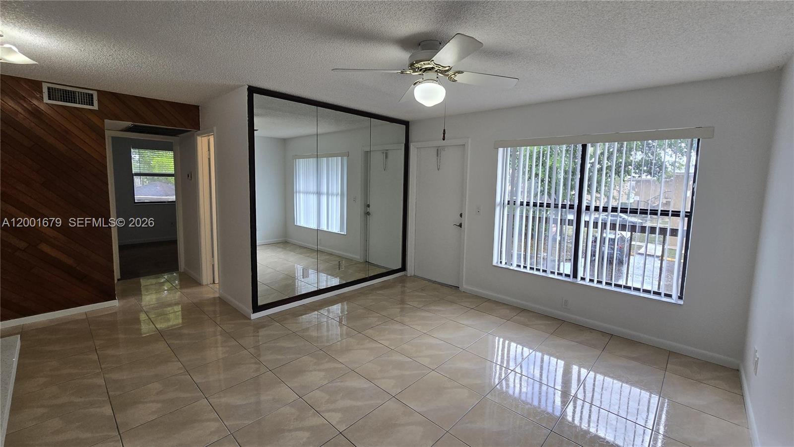 This room features tiled floors, a mirrored wall, a ceiling fan, and large windows — 2605 W 67th Pl # 10, Hialeah FL 33016, HIALEAH, FL