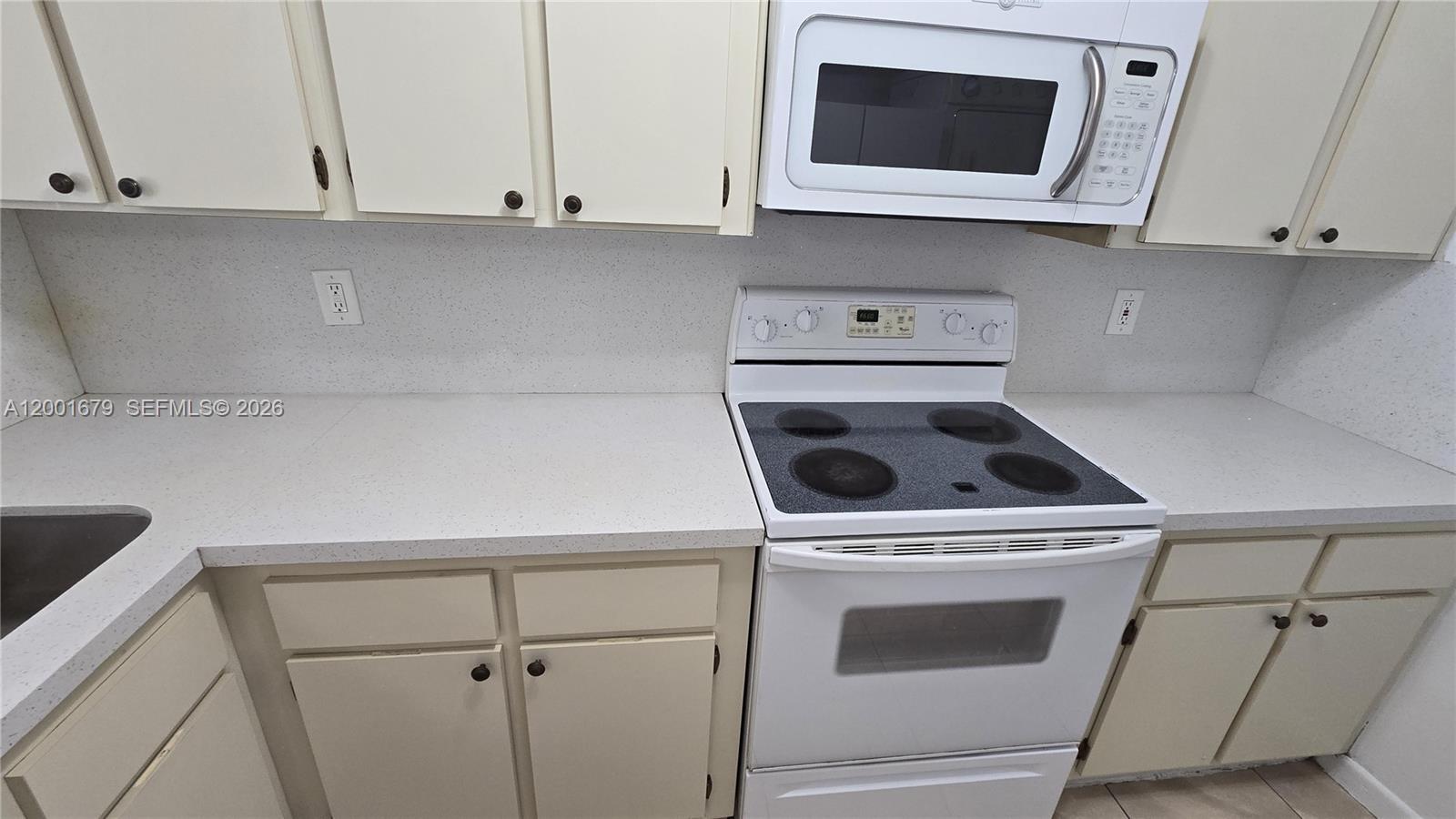 A kitchen features white cabinets, a white electric range, and a speckled countertop — 2605 W 67th Pl # 10, Hialeah FL 33016, HIALEAH, FL