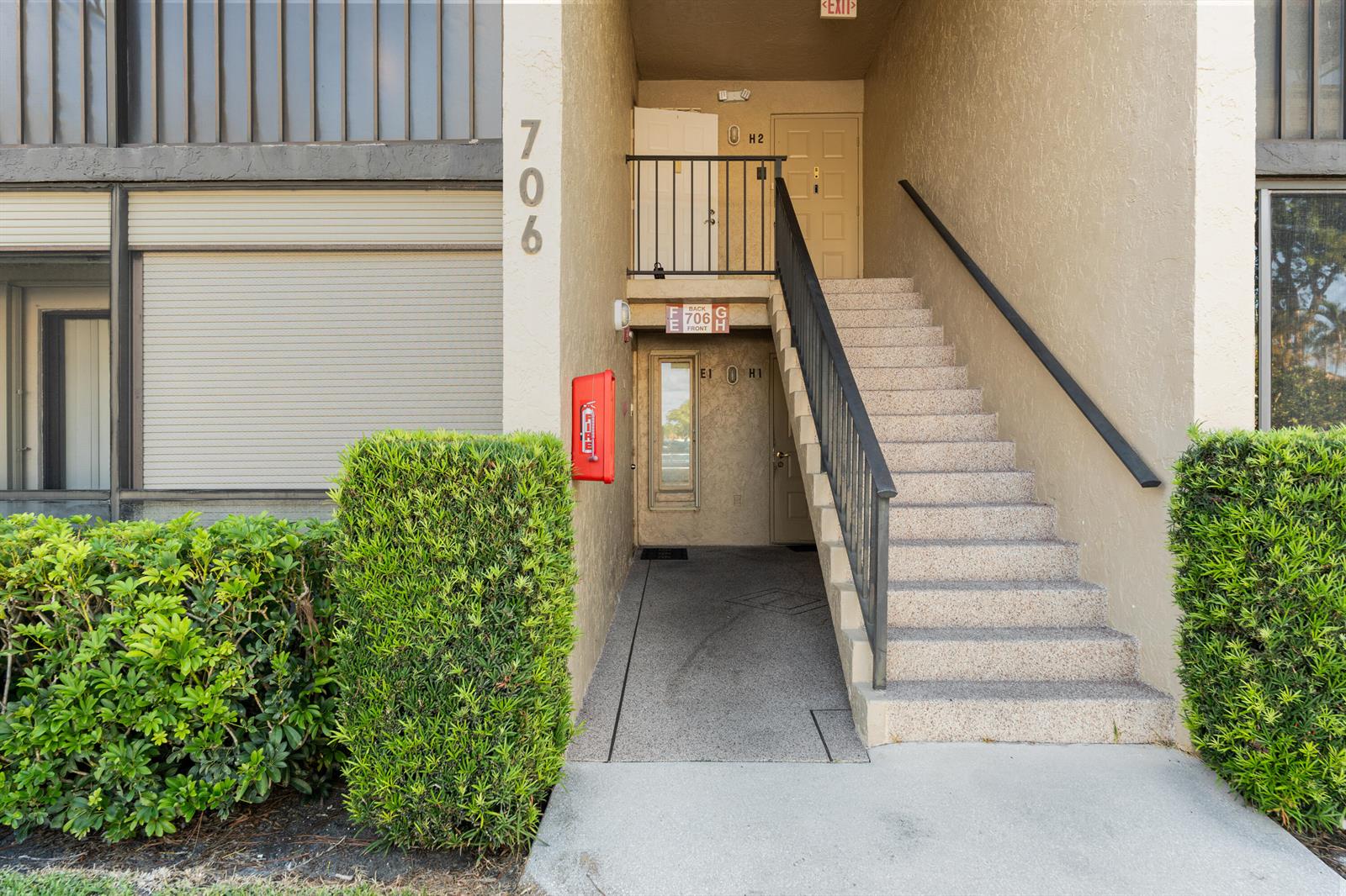 An exterior view of a building entrance with stairs leading to an upper-level door — 706 Sunny Pine Way # E2, FL 33415, FL