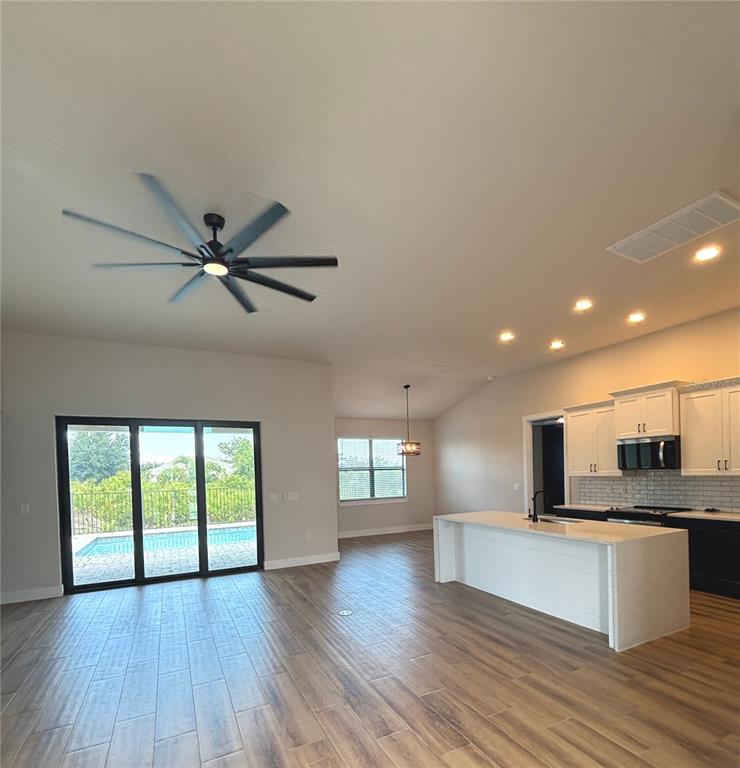 An open-concept kitchen and living area features wood-look tile flooring, a large island, and sliding doors — 13575 ABUTILON LANE, PORT CHARLOTTE, FL