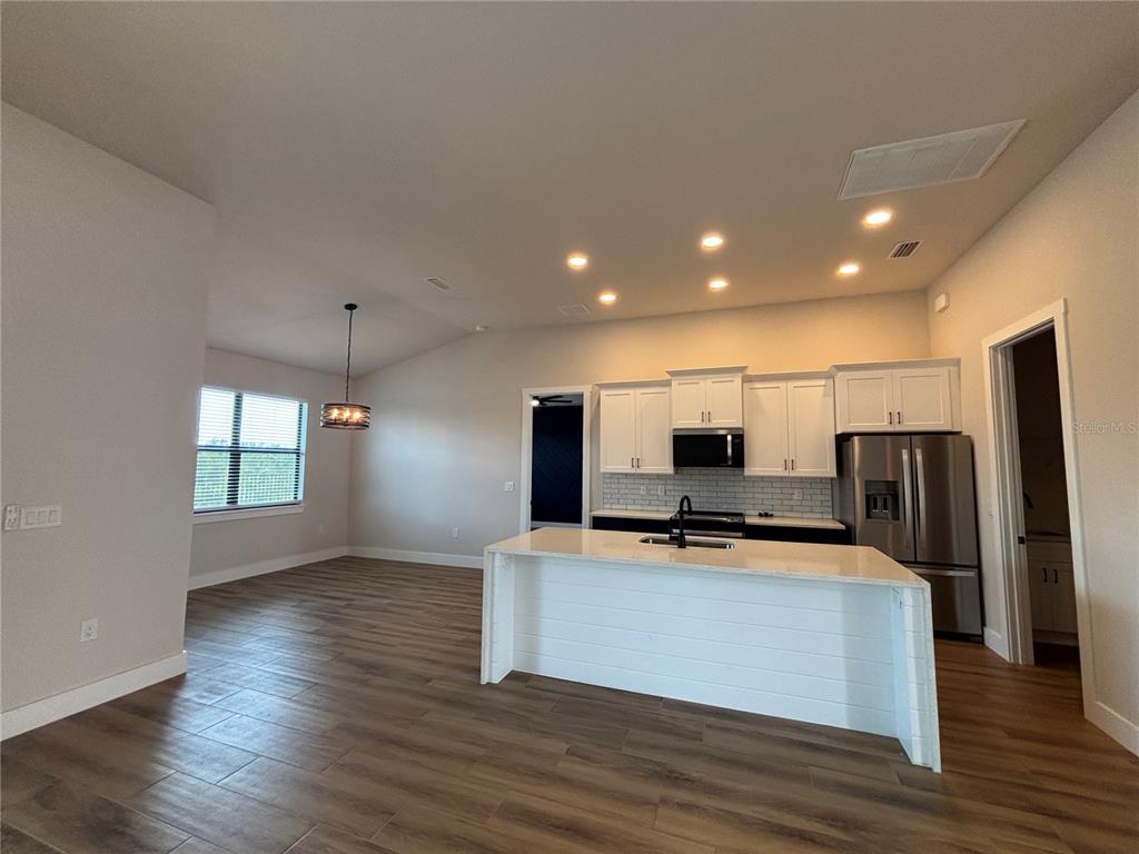 A kitchen with white cabinets, a central island, and wood-look tile flooring — 13575 ABUTILON LANE, PORT CHARLOTTE, FL