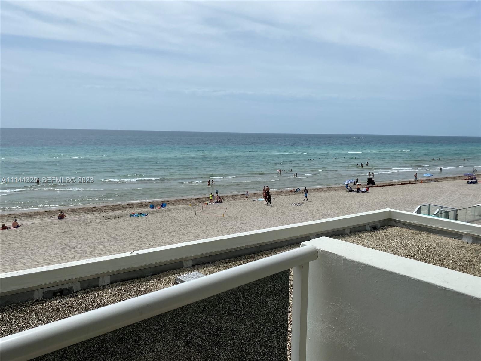A view of a sandy beach and ocean from a white balcony railing — 3725 S Ocean Dr # 301, Hollywood FL 33019, HOLLYWOOD, FL