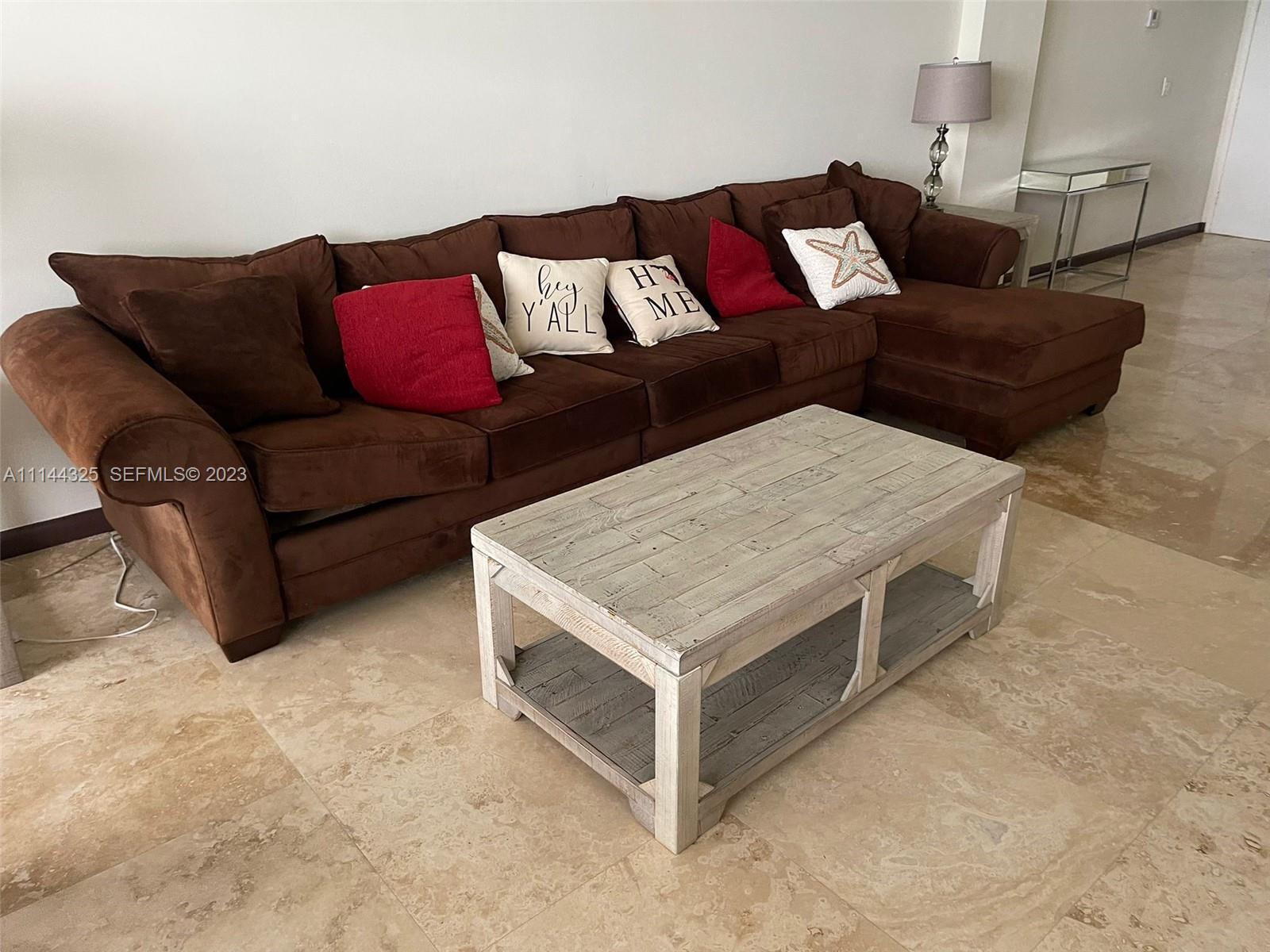 A brown sectional sofa and a rustic wooden coffee table sit on a tiled floor — 3725 S Ocean Dr # 301, Hollywood FL 33019, HOLLYWOOD, FL