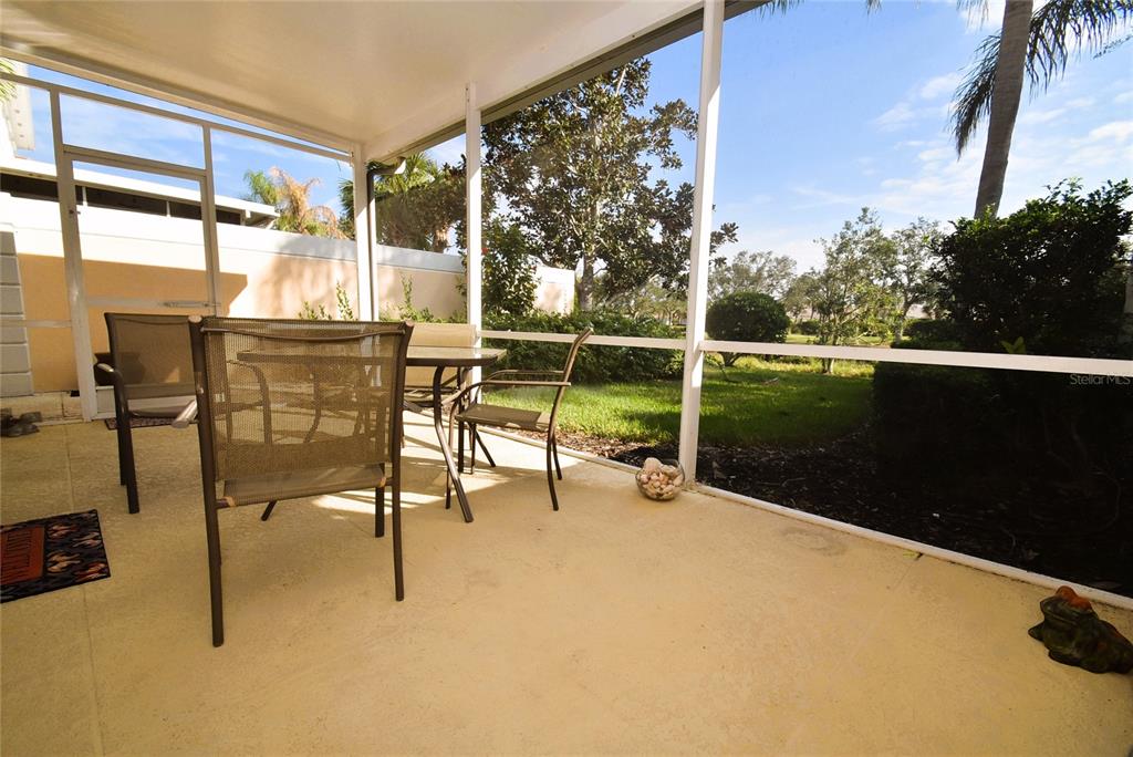 A screened-in patio features a table, chairs, and a view of a grassy lawn — 7624 BERGAMO AVENUE UNIT 4B, SARASOTA, FL