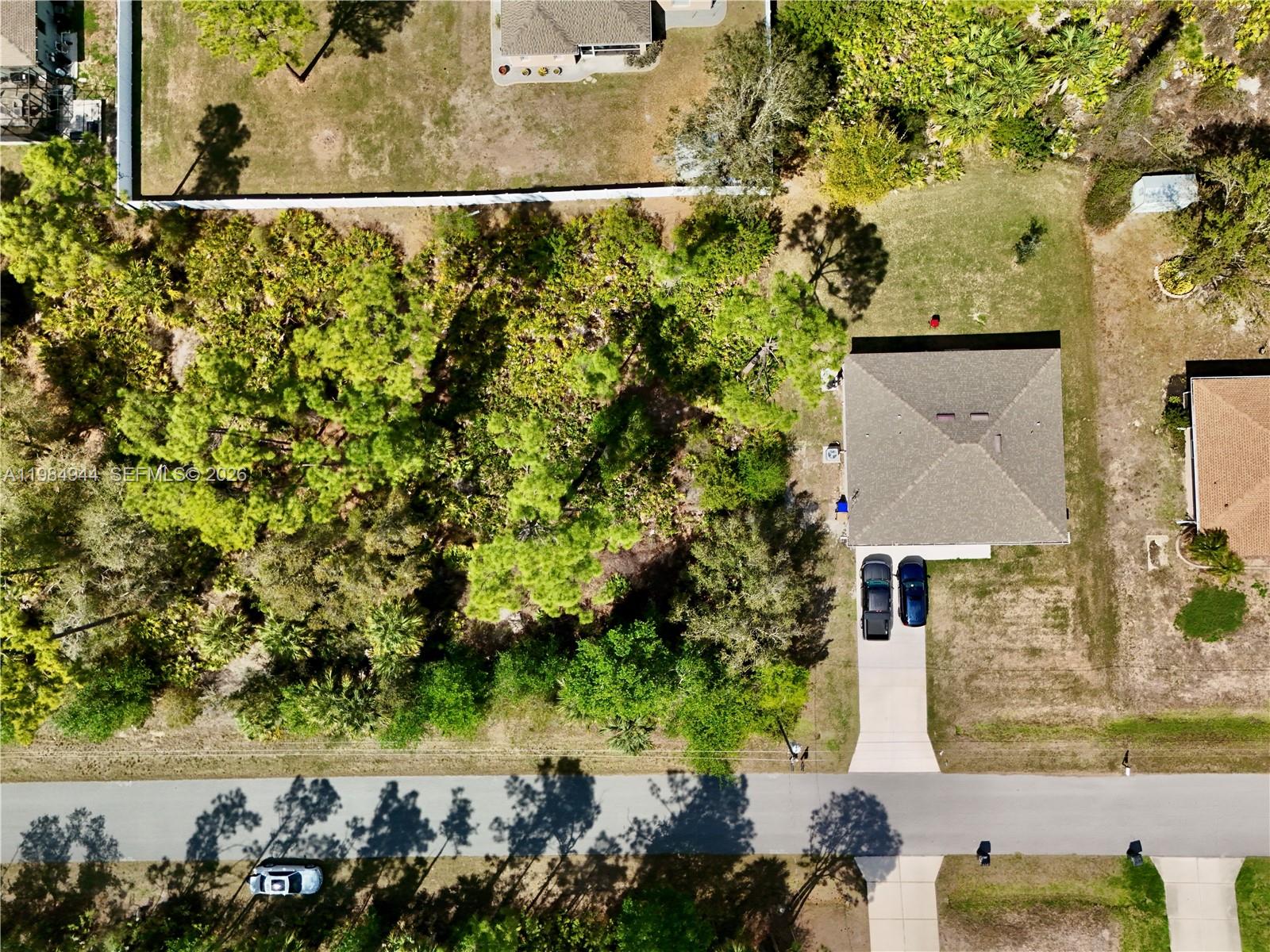 An aerial view shows a house with a driveway and two cars beside a wooded lot — 0 APOLLO AVE, North Port FL 34286, NORTH PORT, FL