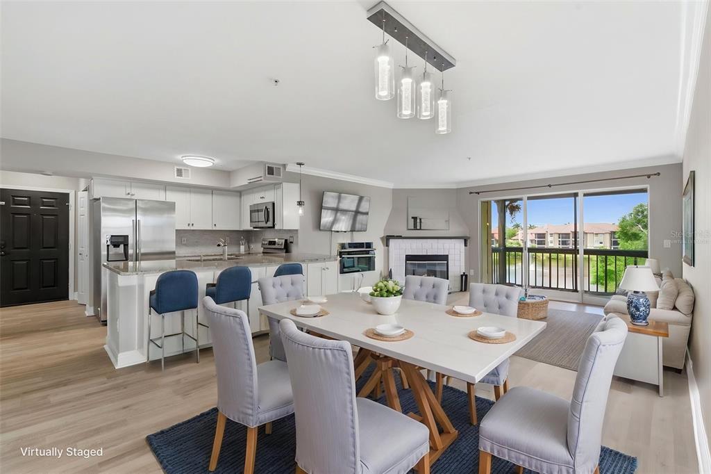 An open-concept living and dining area features a kitchen, fireplace, and sliding glass balcony doors — 2400 FEATHER SOUND DRIVE UNIT 1136, CLEARWATER, FL