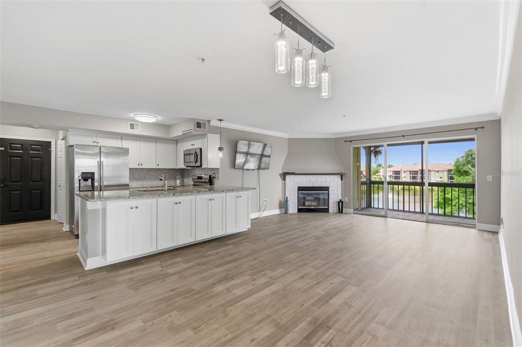An open-concept kitchen and living area with white cabinets, stainless steel appliances, and a fireplace — 2400 FEATHER SOUND DRIVE UNIT 1136, CLEARWATER, FL