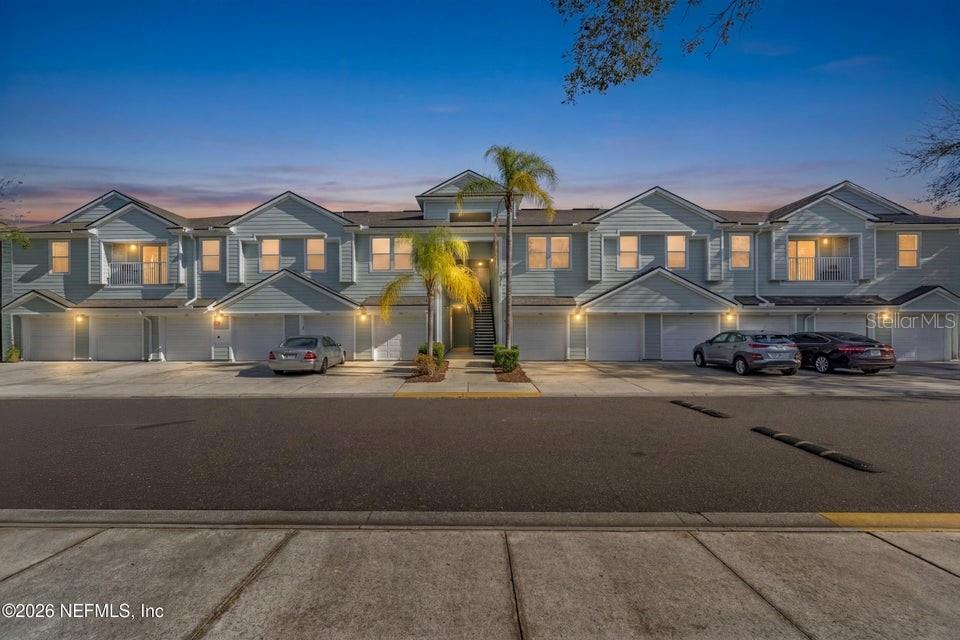 A multi-unit residential building with light blue siding, attached garages, and a central staircase — 7047 DEER LODGE CIRCLE UNIT 108, JACKSONVILLE, FL